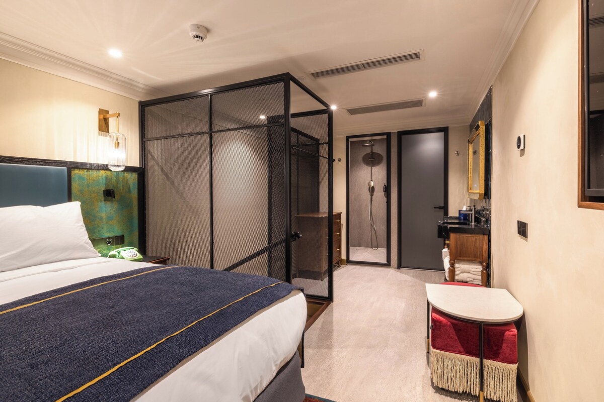 Une chambre d’hôtel comprenant un lit, un bureau, un espace douche et une salle de bain.