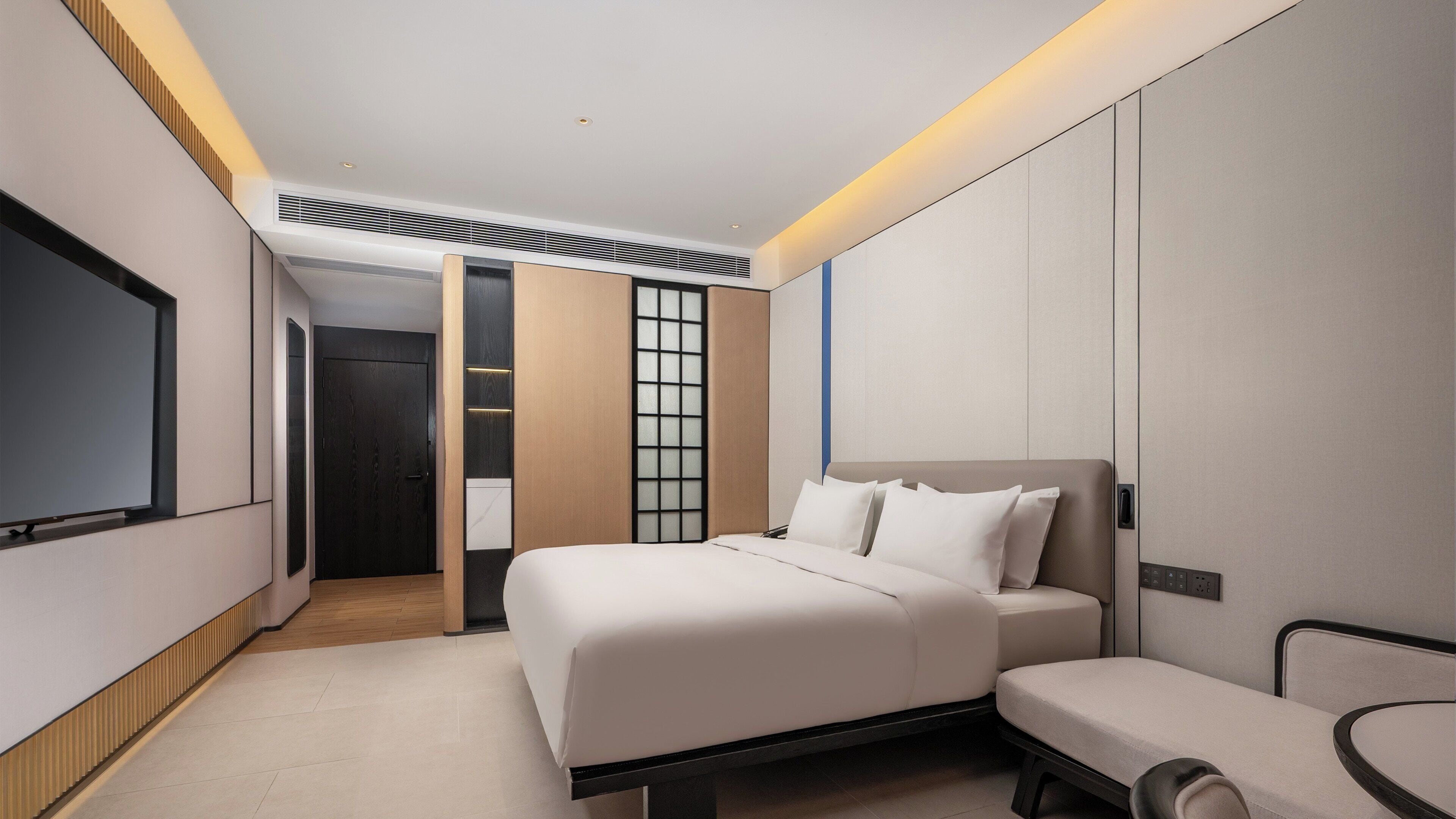 Una habitación de hotel moderna con una cama grande, una mesita de noche, un televisor y una puerta corredera que da al baño.