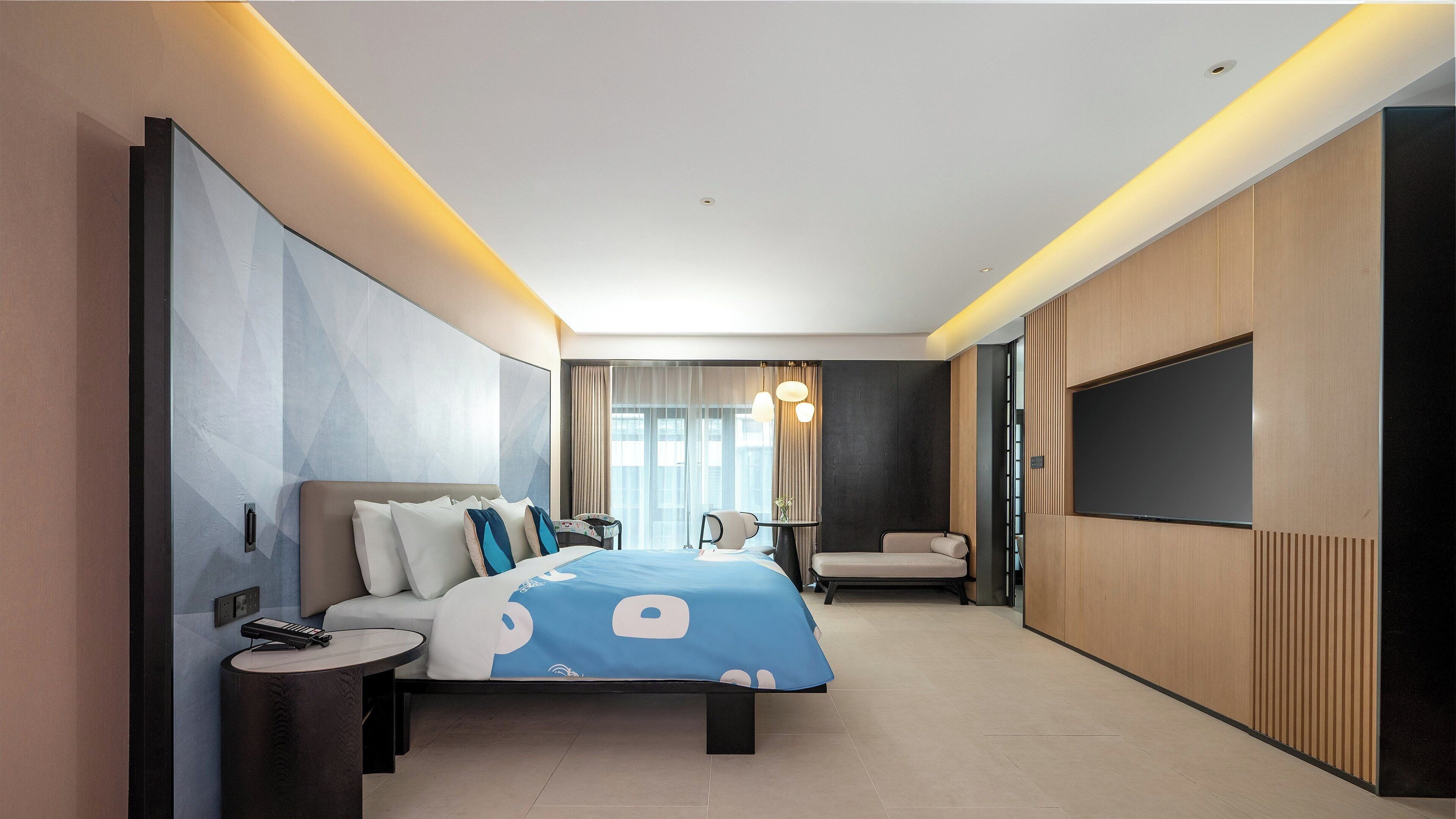 Una habitación de hotel moderna con una cama grande, un televisor, un escritorio y una silla.