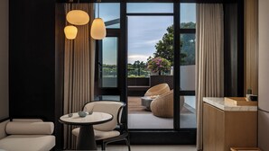 A modern room with a large sliding glass door leading to an outdoor balcony. Inside, there is a round table with chairs, a small sofa, and a wooden side table. - Holiday Inn Express Guangzhou Baiyun Airport T2 by IHG (Guangzhou)