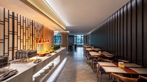 A modern restaurant with a long counter, multiple tables, and a view of the city through large windows. - Holiday Inn Express Guangzhou Baiyun Airport T2 by IHG (Guangzhou)