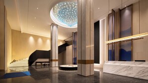 A modern lobby with a central staircase, a circular chandelier, and a reception desk. - Holiday Inn Express Guangzhou Baiyun Airport T2 by IHG (Guangzhou)