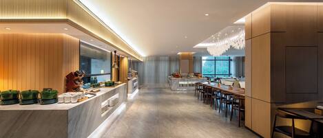 A modern kitchen with a marble countertop, wooden cabinets, and a large window providing a view of the outdoors.