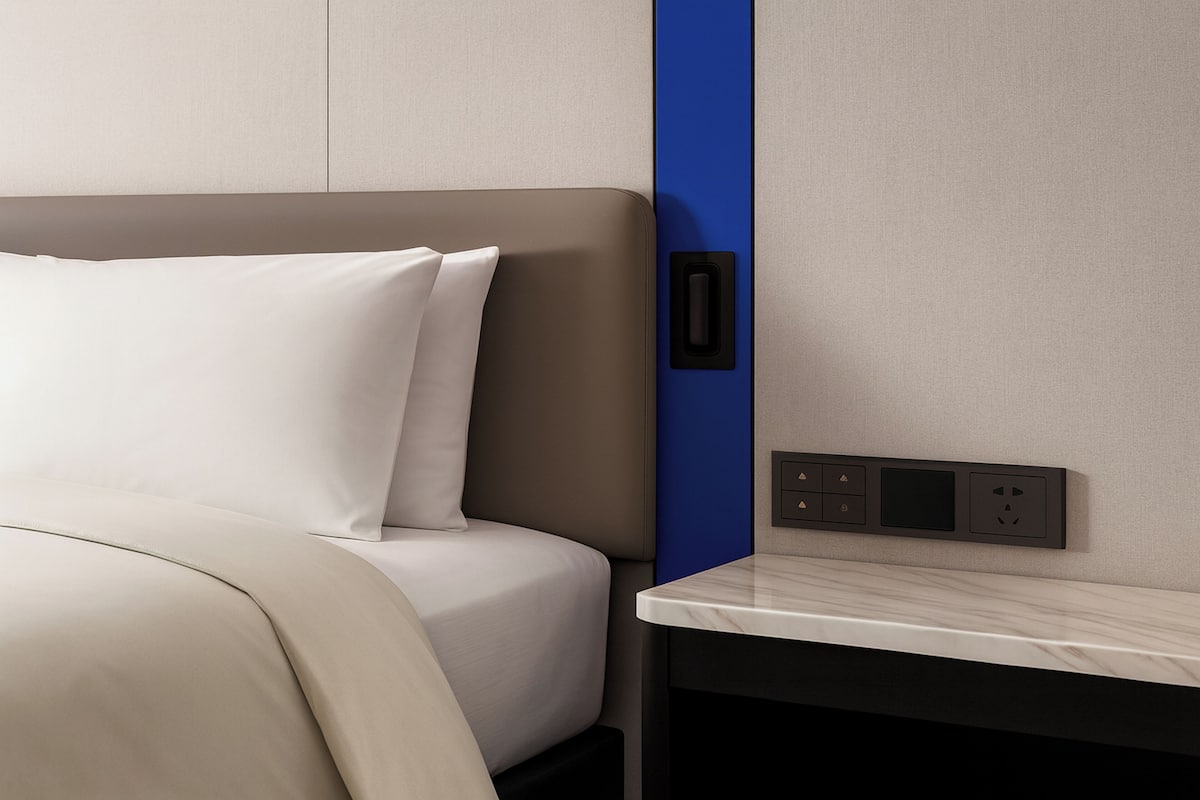 Ein modernes Hotelzimmer mit Bett, Nachttisch und einer an der Wand montierten Steuerung.