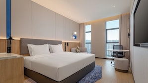 Una habitación de hotel moderna con una cama grande, un escritorio, una silla y un televisor.