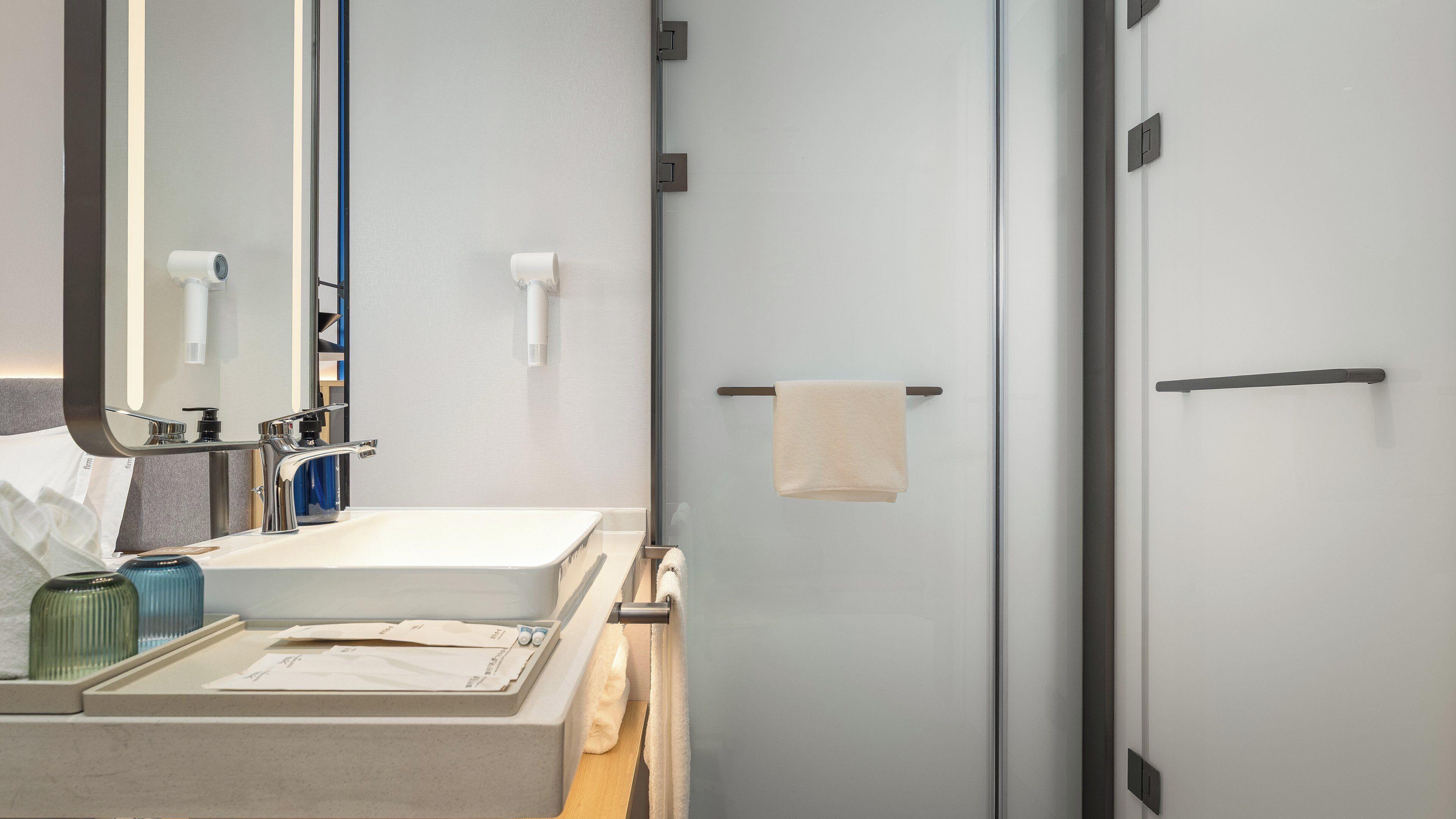 A modern bathroom with a large mirror, a sink, and a towel rack.