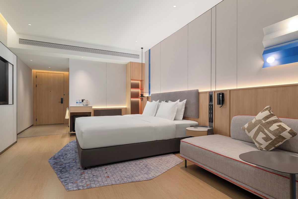 Une chambre d’hôtel moderne équipée d’un grand lit, d’un canapé, d’un bureau et d’un téléviseur à écran plat.