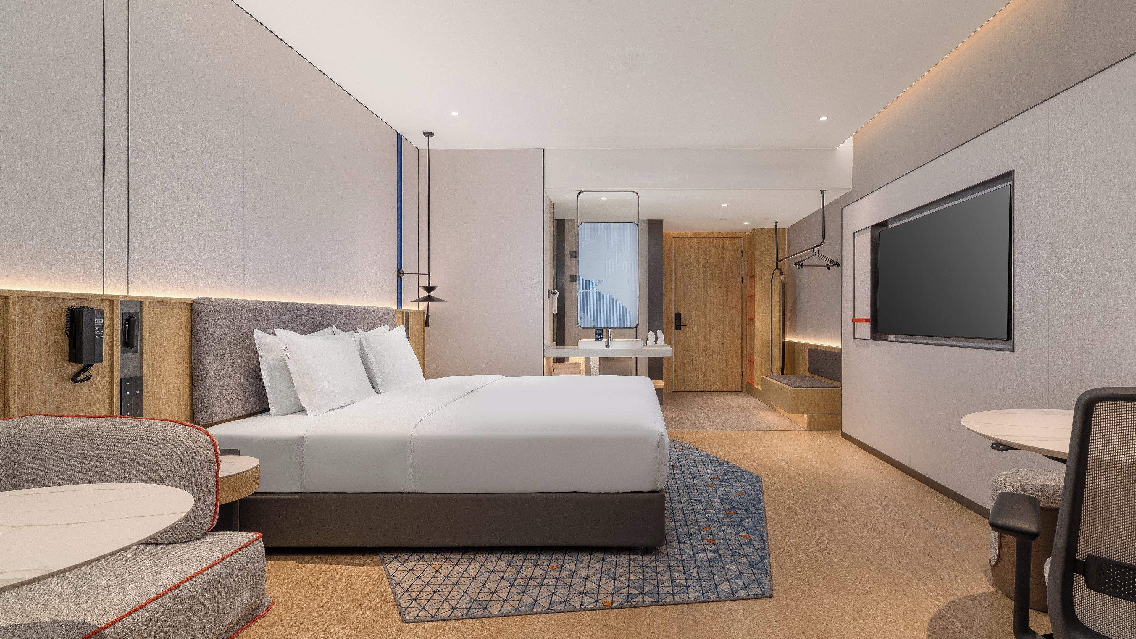 Une chambre d’hôtel moderne équipée d’un grand lit, d’un bureau, d’une chaise, d’une télévision et d’un téléphone.