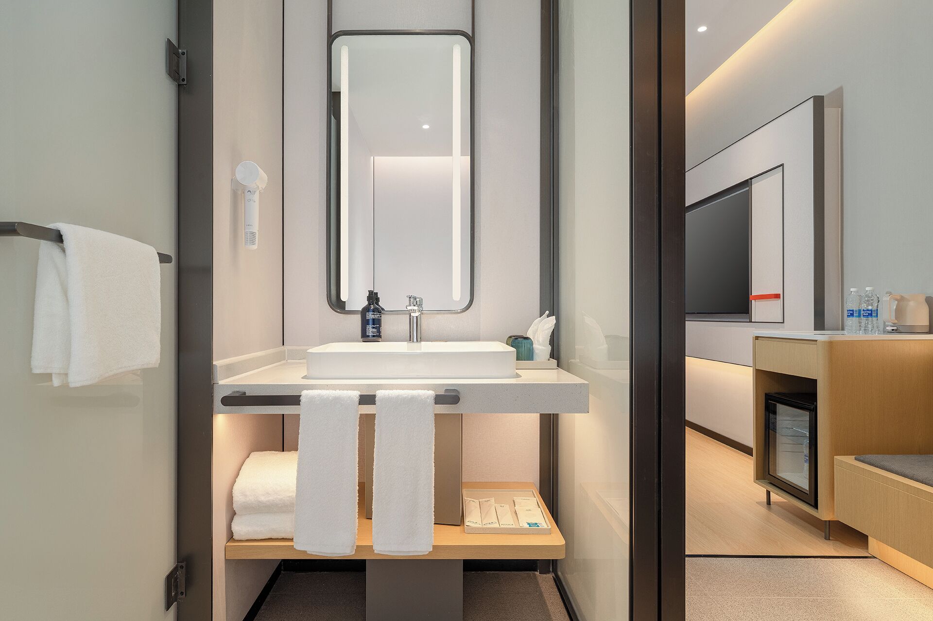 Un baño moderno con lavabo, espejo, toallero y un estante con artículos de aseo.