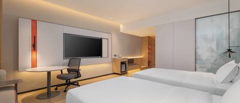 Una habitación de hotel moderna con dos camas, un escritorio, un televisor y un minibar.