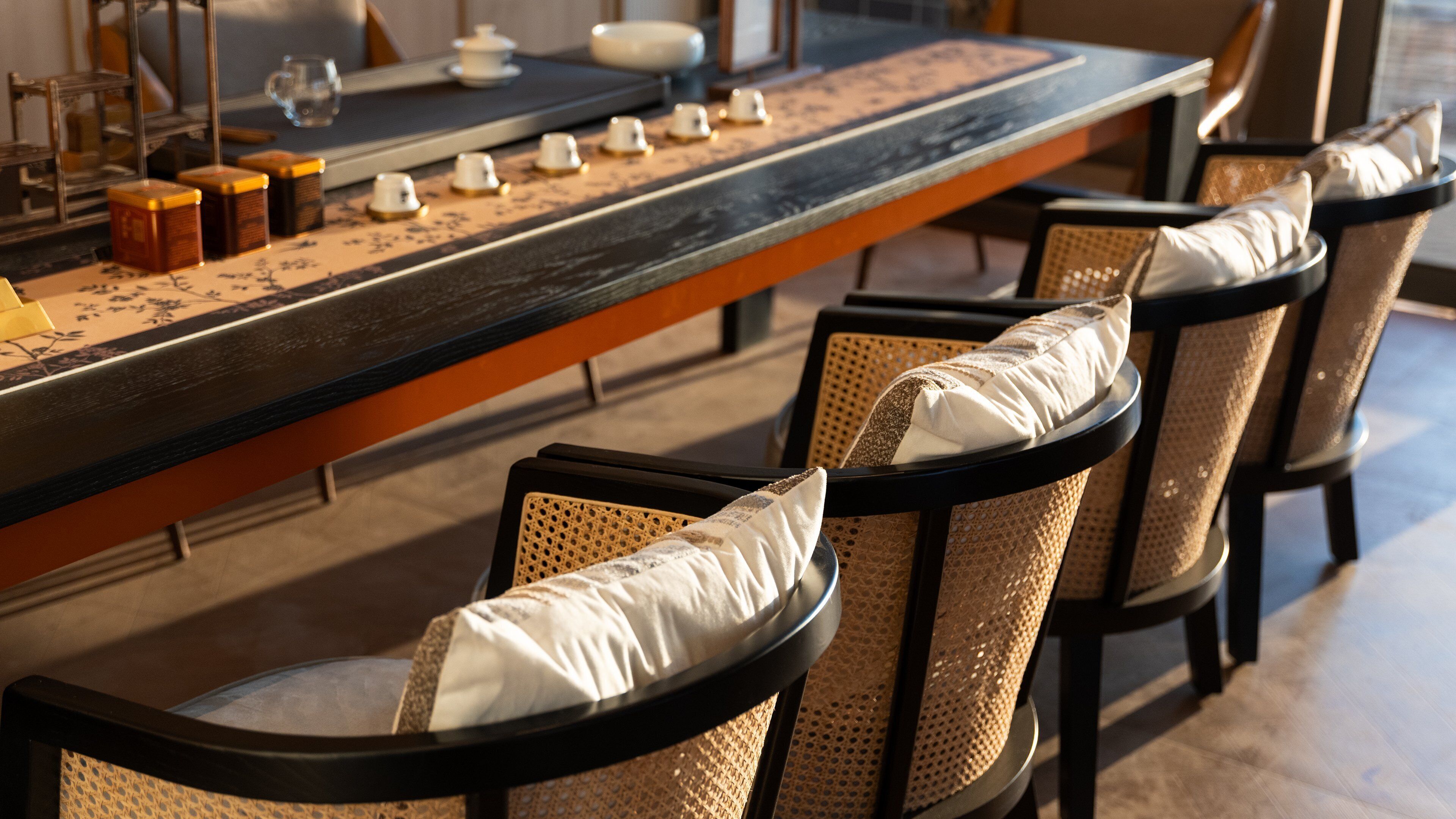 A bar area with a long counter, several chairs with cushioned seats, and a decorative table with small vases and a glass.