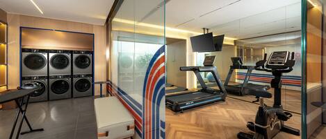Ein Hotelzimmer mit Fitnessbereich, inklusive Laufband, Ergometer und einer Waschmaschine.