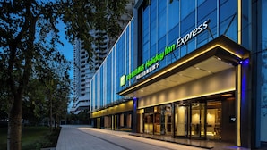 A modern hotel facade with a prominent sign for Holiday Inn Express, featuring a glass entrance and illuminated signage. - Holiday Inn Express Shenzhen Sports Center by IHG (Shenzhen)