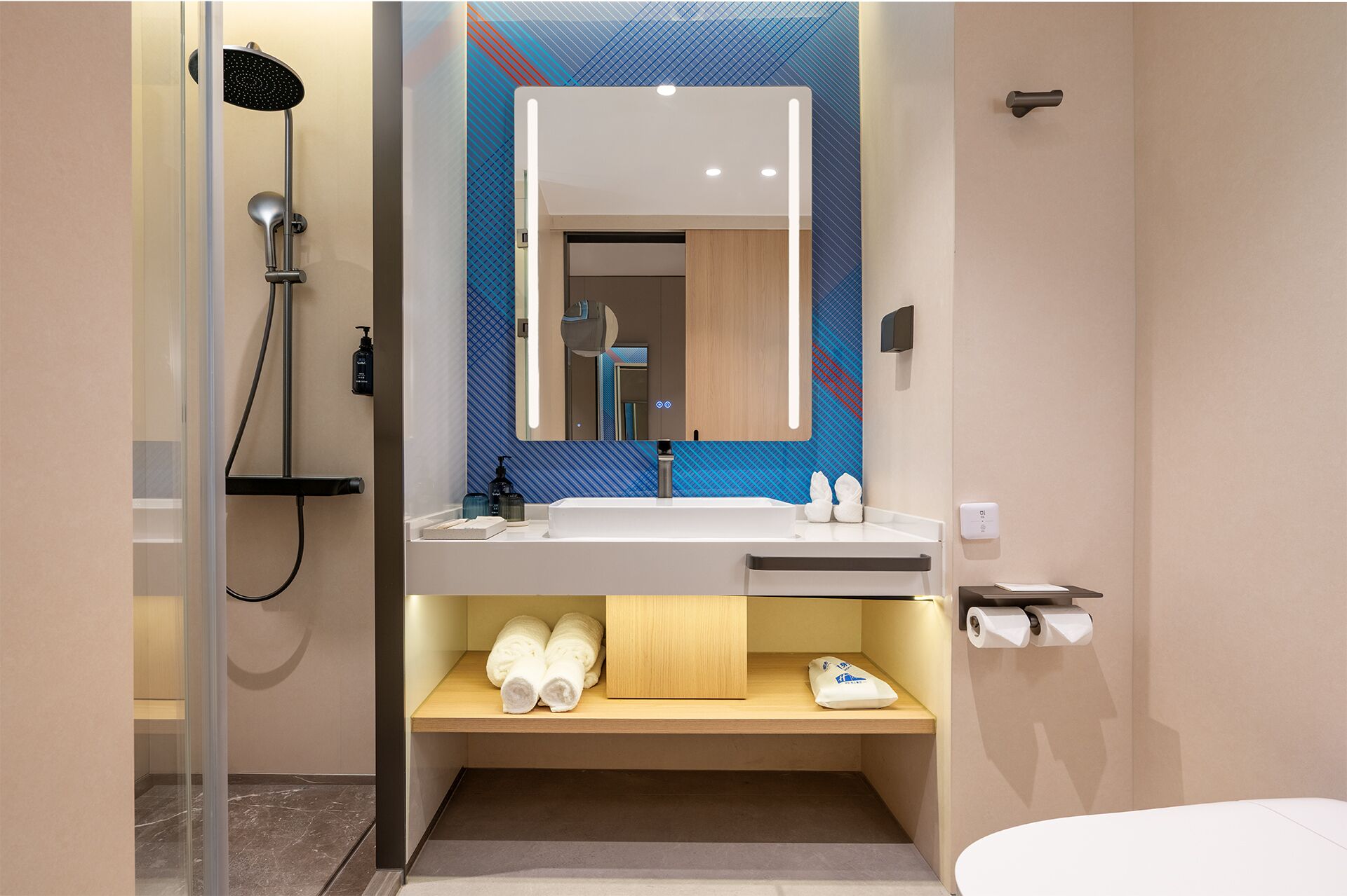 A modern bathroom with a glass-enclosed shower, a large mirror, a sink with a wooden vanity, and a toilet paper holder.
