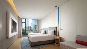 A modern hotel room with a large bed, a sofa, a small table, and a view of the cityscape. - Holiday Inn Express Shenzhen Sports Center by IHG (Shenzhen)