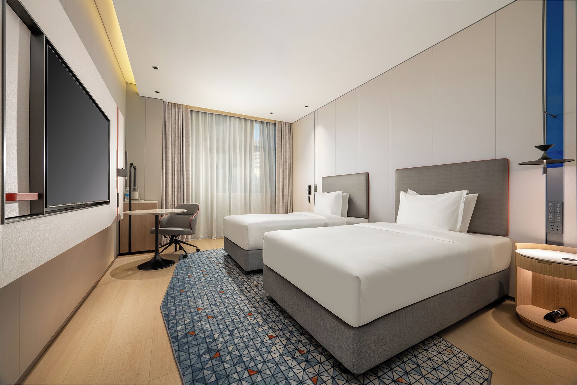 A modern hotel room with two beds, a desk, and a large window with curtains.
