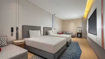 Een moderne hotelkamer met twee bedden, een bank, een kleine tafel, een bureau en een televisie.