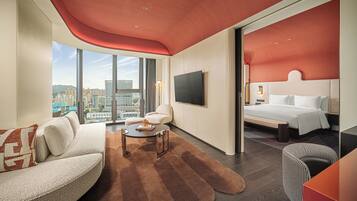 Een moderne hotelkamer met een groot bed, een bank, een bijzettafeltje en een televisie.