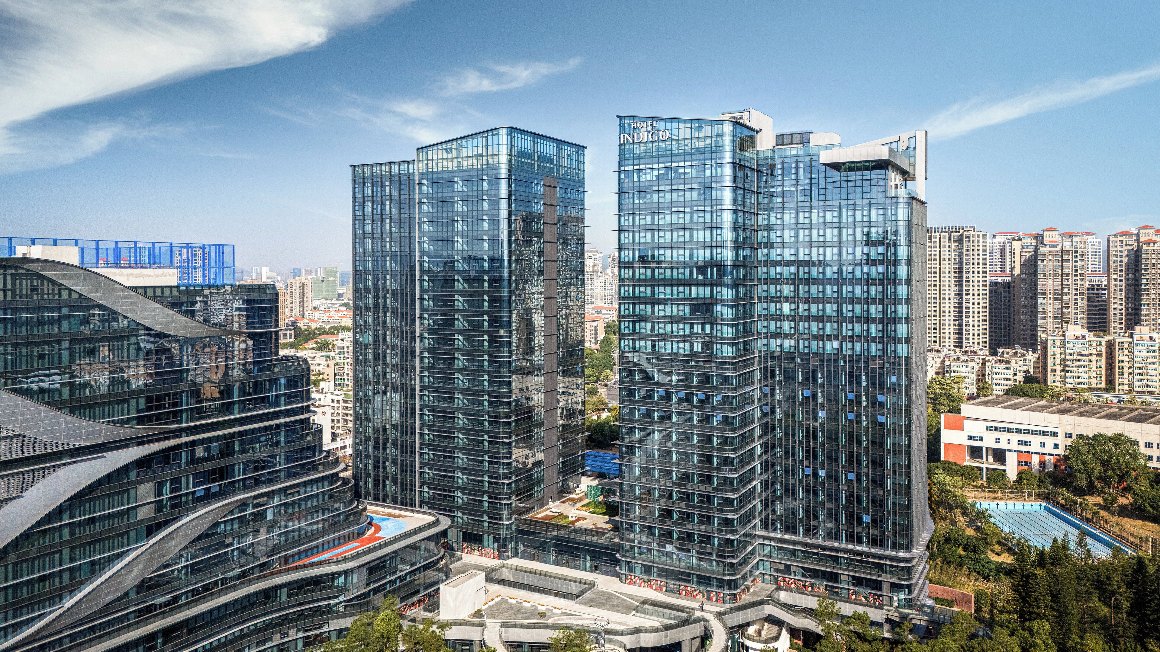 Two high-rise buildings with reflective glass facades, surrounded by other high-rise buildings and a clear sky.