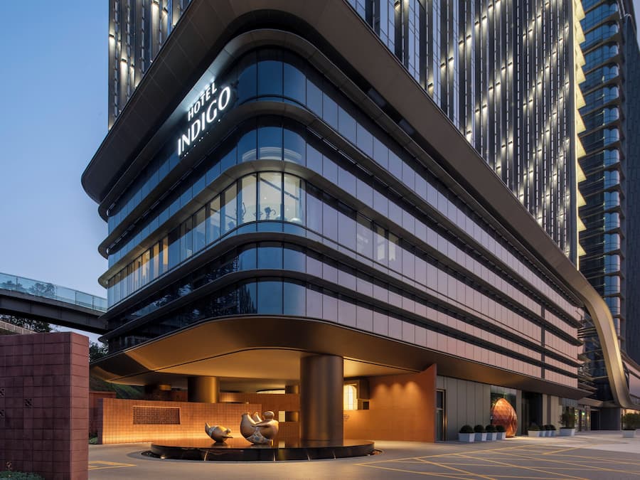 Un hôtel moderne à la façade incurvée, doté de grandes fenêtres et d’une entrée imposante.