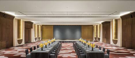 Un salón de conferencias con una larga mesa, sillas y una gran pantalla al frente.
