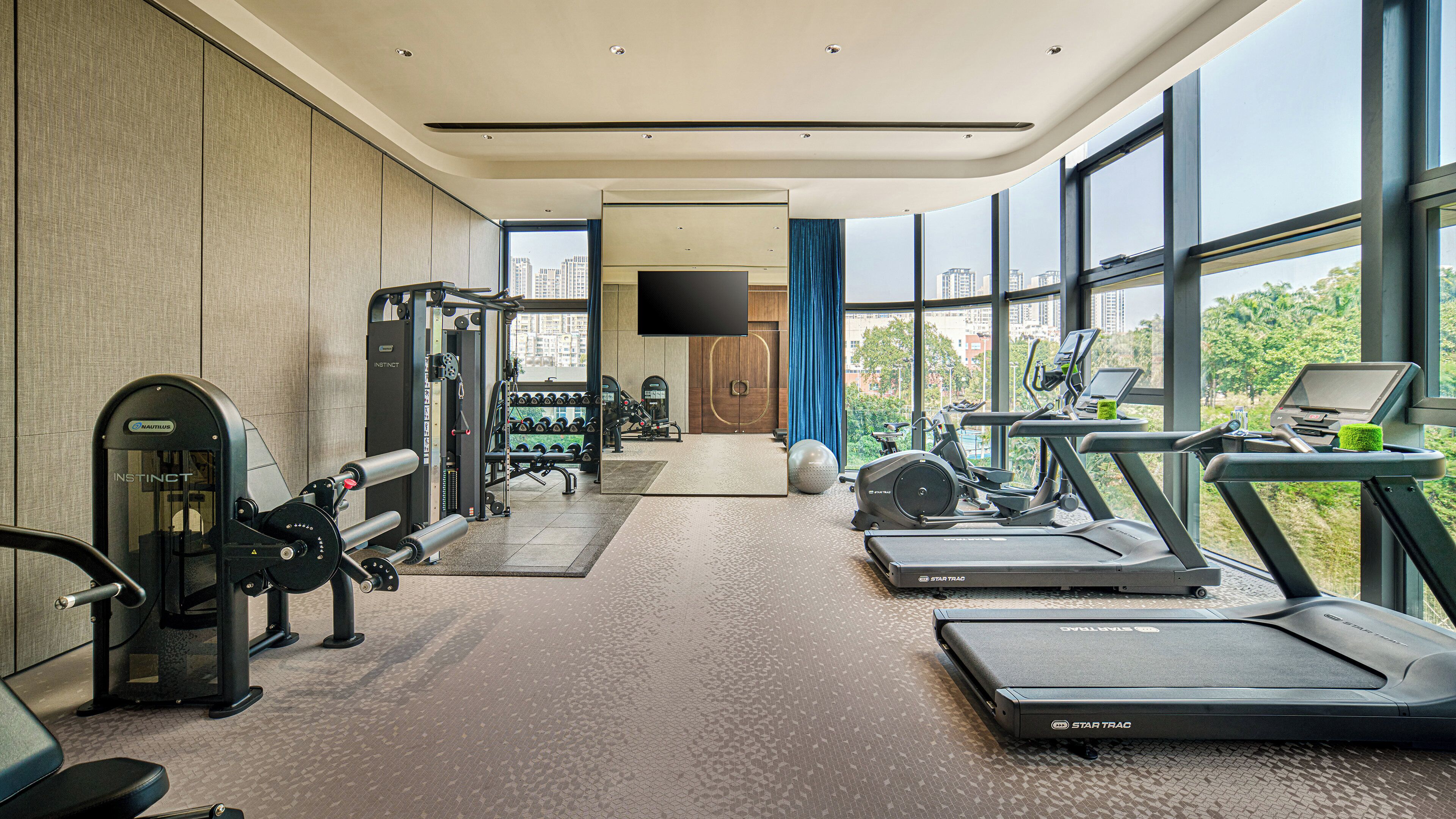 A modern gym with treadmills, weight machines, and a mirror.