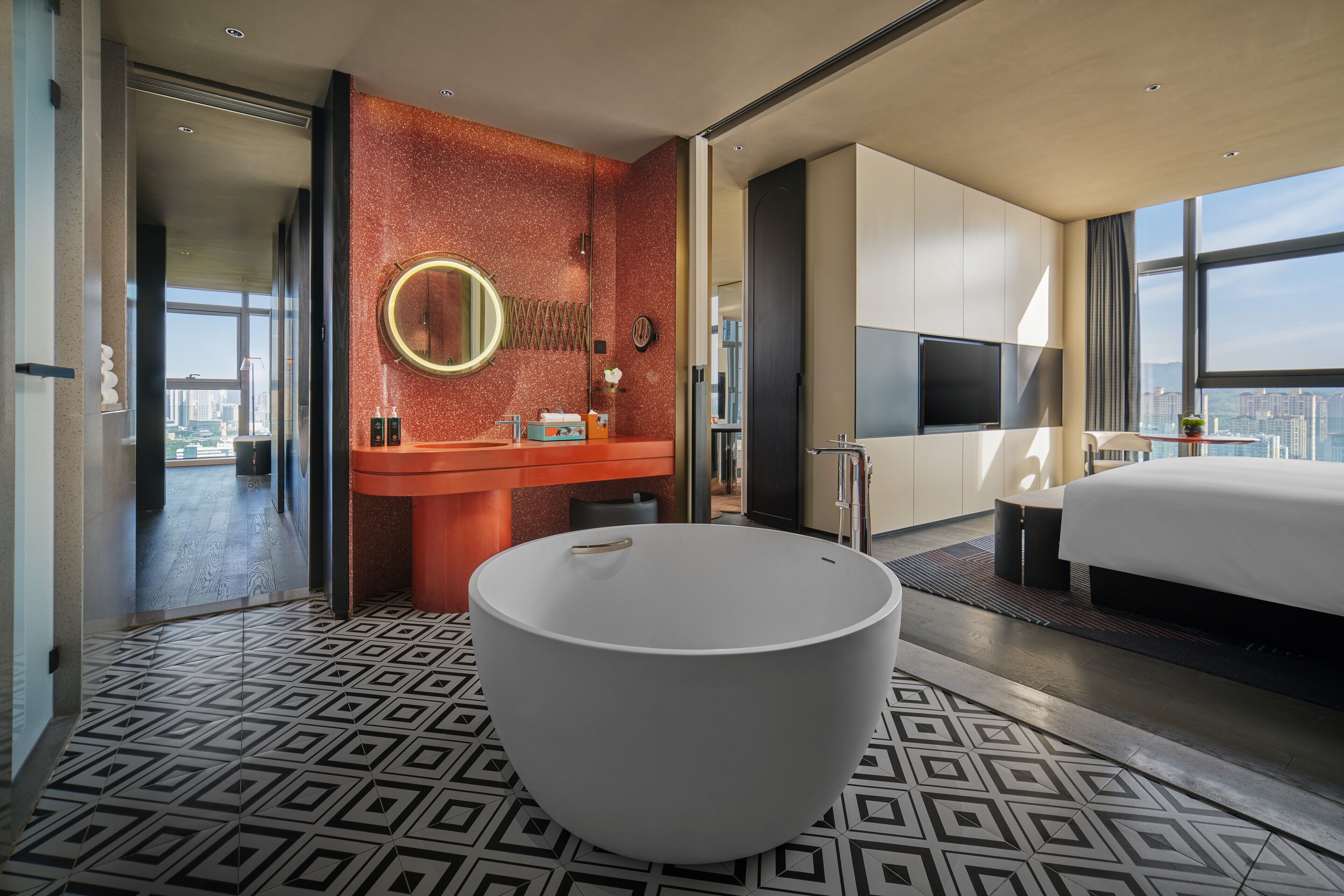 Une chambre d’hôtel moderne dotée d’une grande baignoire, d’une coiffeuse avec miroir, d’un lit et d’une télévision.