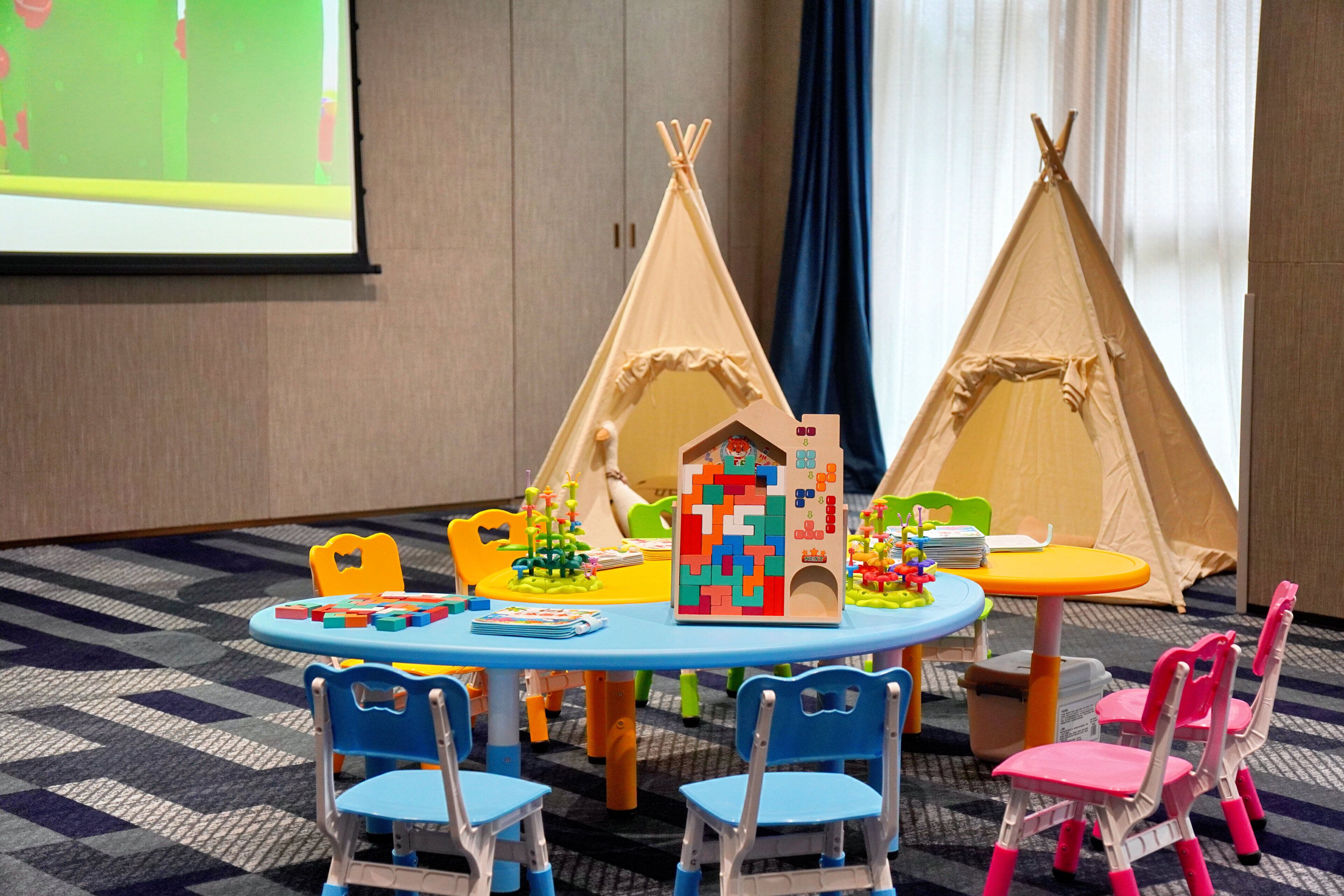 Un área de juegos infantiles con una mesa redonda, sillas y estructuras de juego.