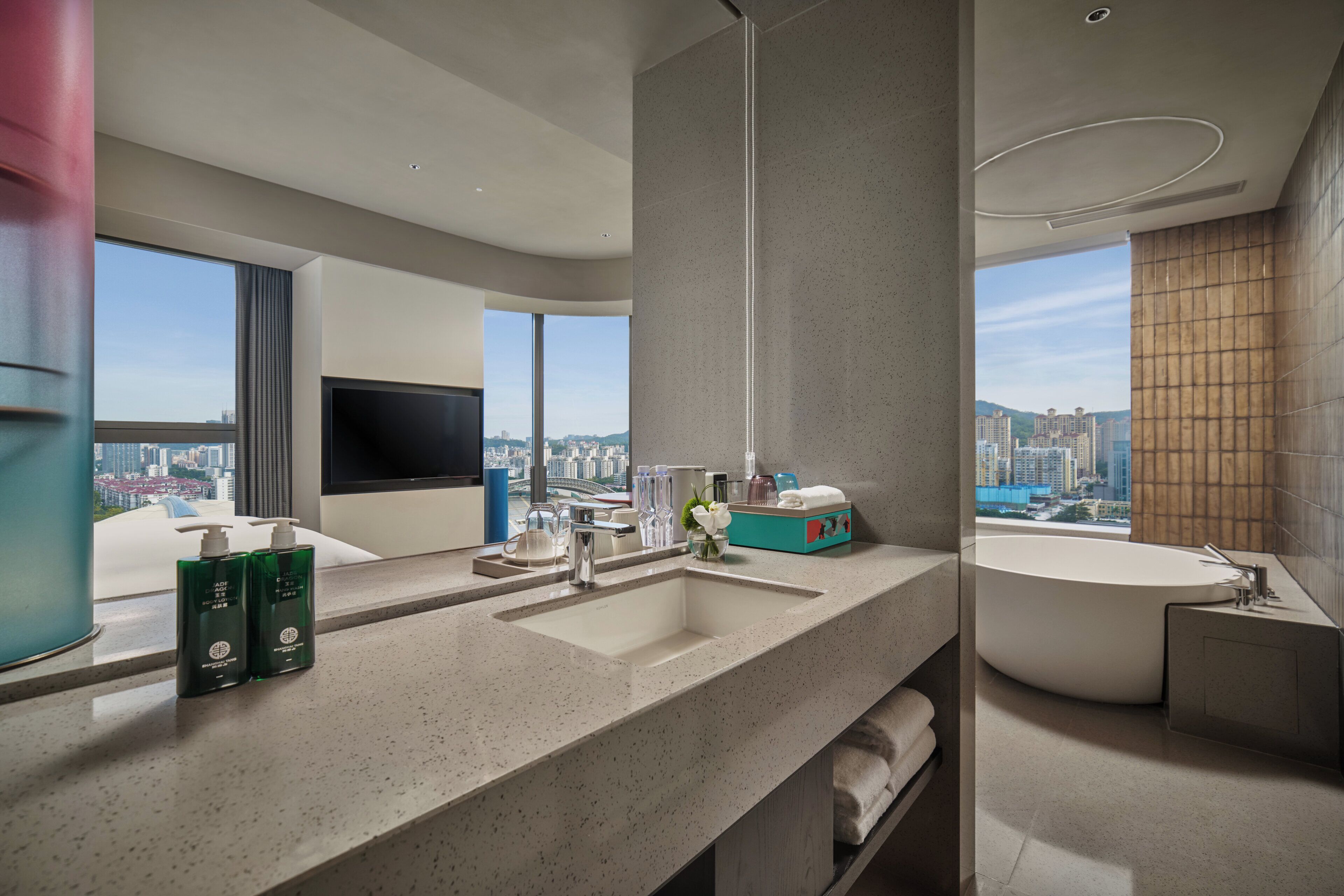 Un baño moderno con un lavamanos grande, una bañera y un ventanal con vista a la ciudad.