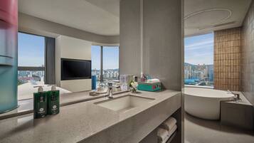 Un baño moderno con un lavamanos grande, una bañera y un ventanal con vista a la ciudad.