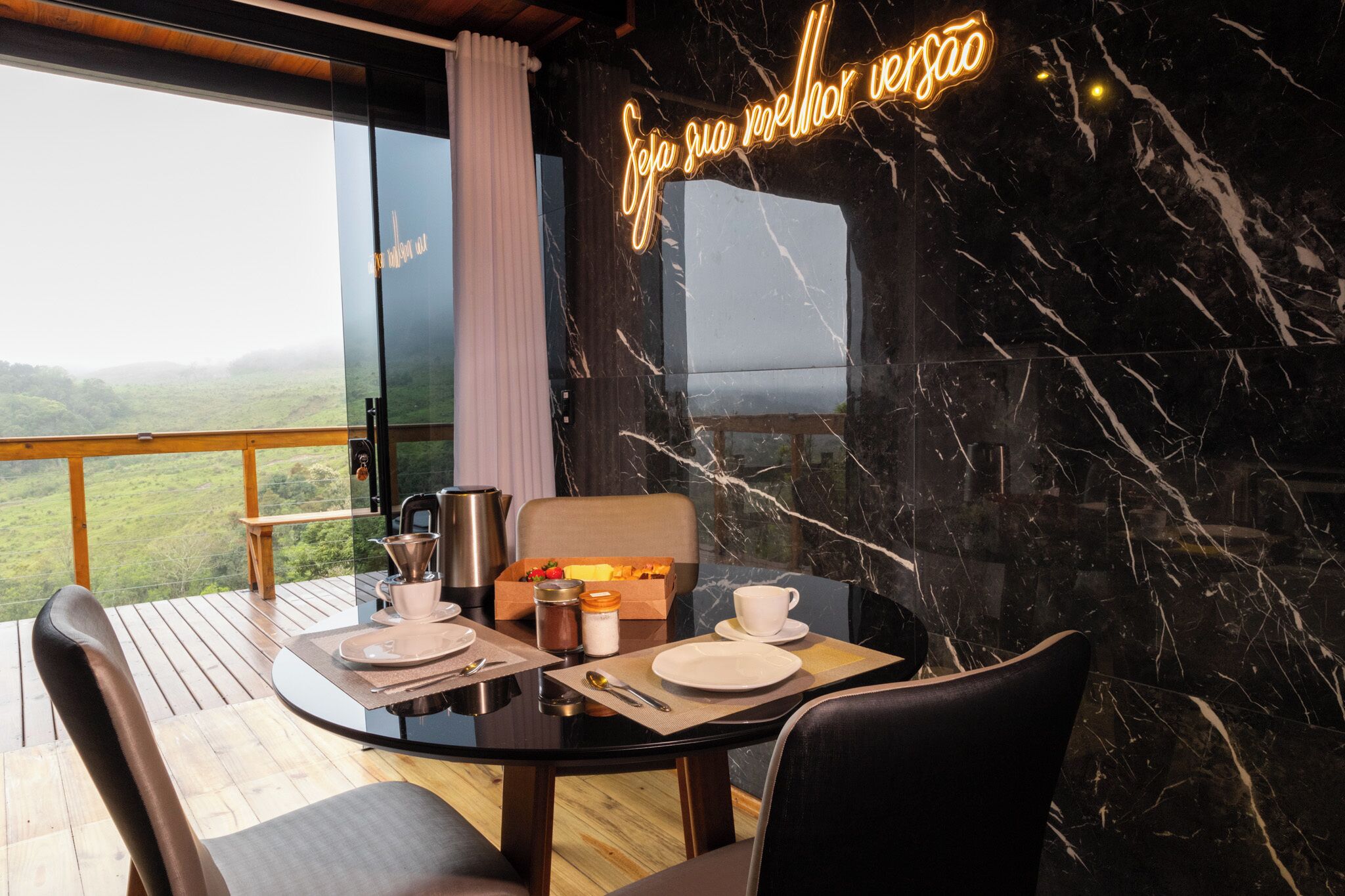 A dining area with a table set for two, a marble wall, and a neon sign.