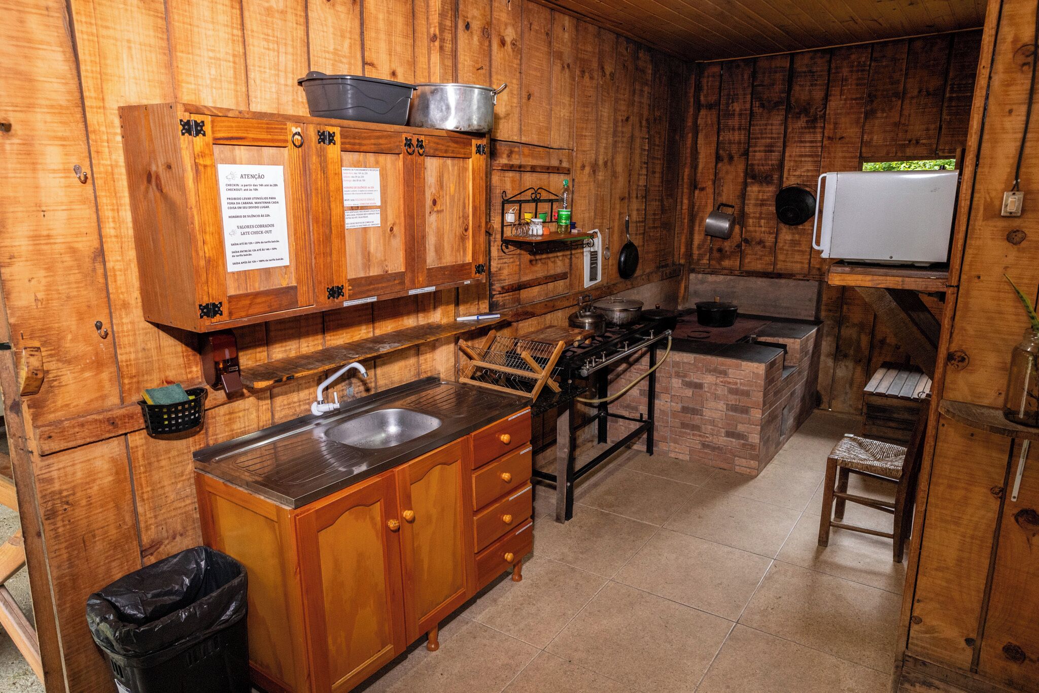 A rustic kitchen with wooden cabinets, a sink, a stove, and a white refrigerator.