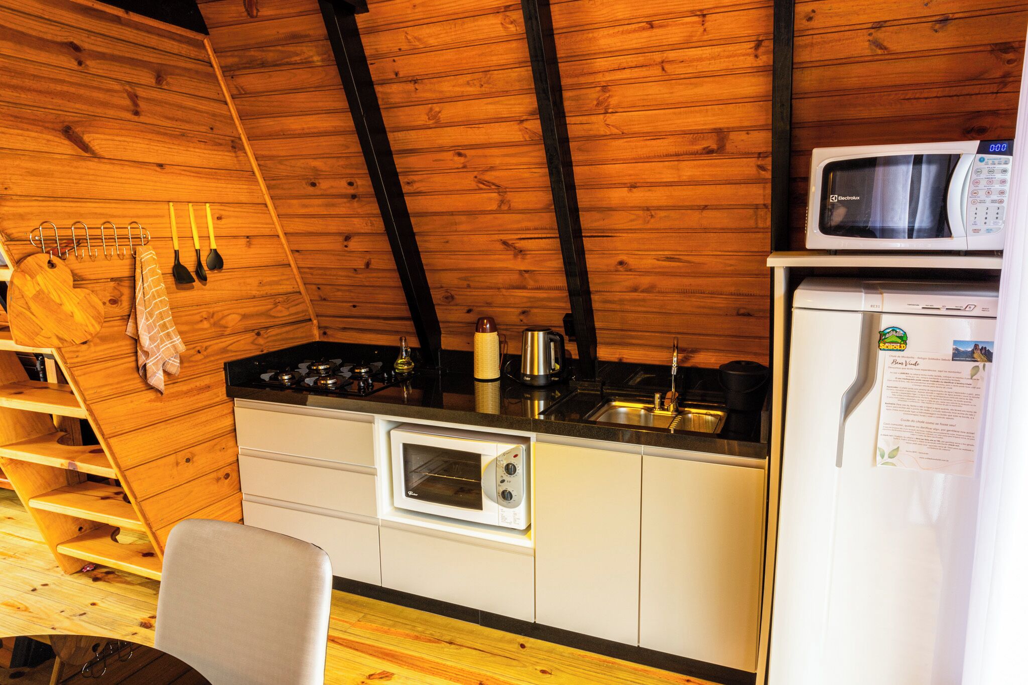Una cucina compatta con pareti in legno, un forno a microonde, forno integrato e frigorifero.