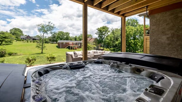 Jacuzzi amb vista a un jardí verd i cases al fons.
