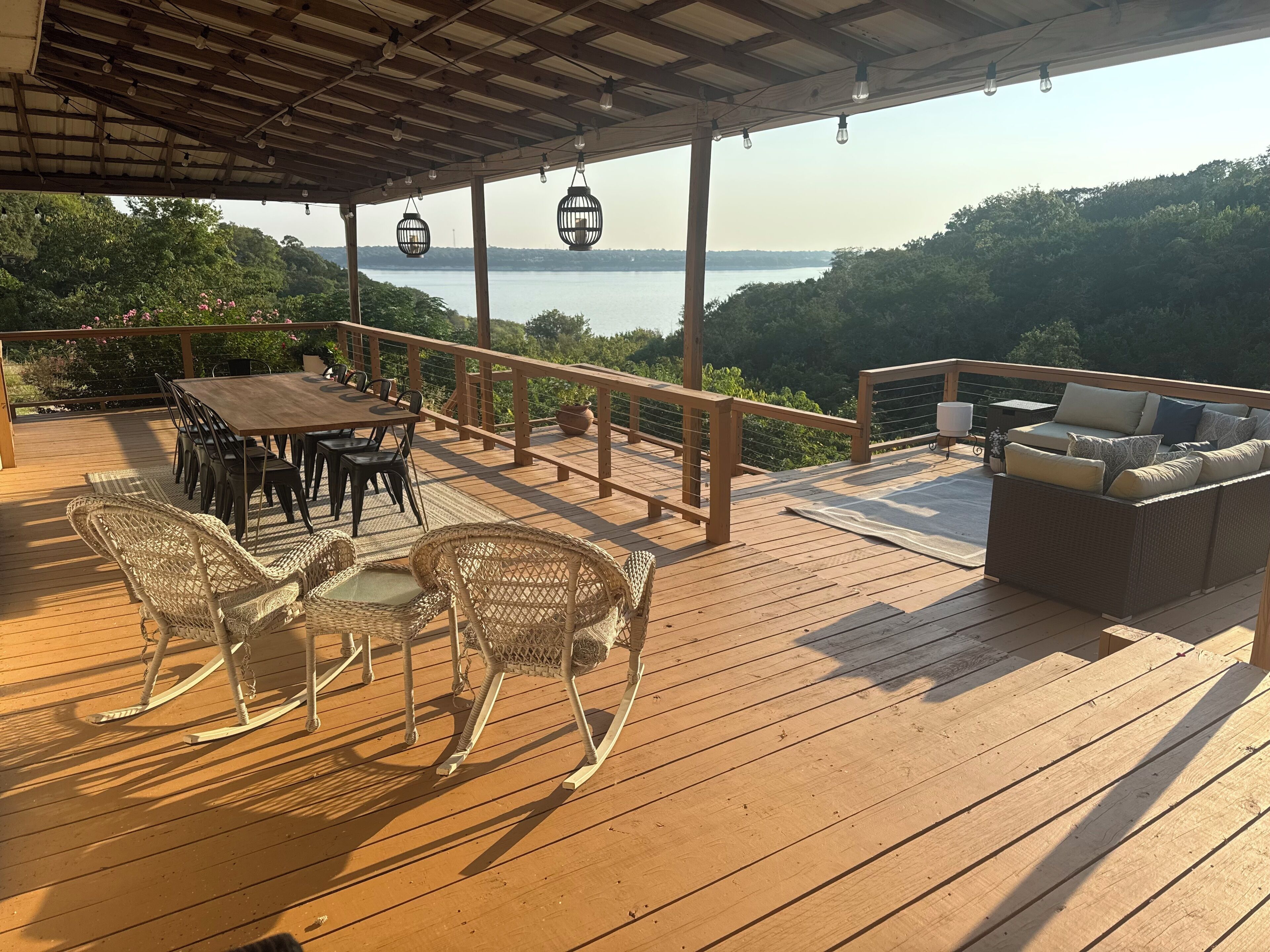 Une terrasse en bois avec une table et des chaises, un canapé et une vue sur l’eau.