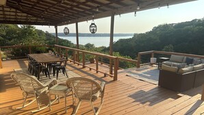Een houten terras met een tafel, stoelen, een bank en uitzicht op het water.
