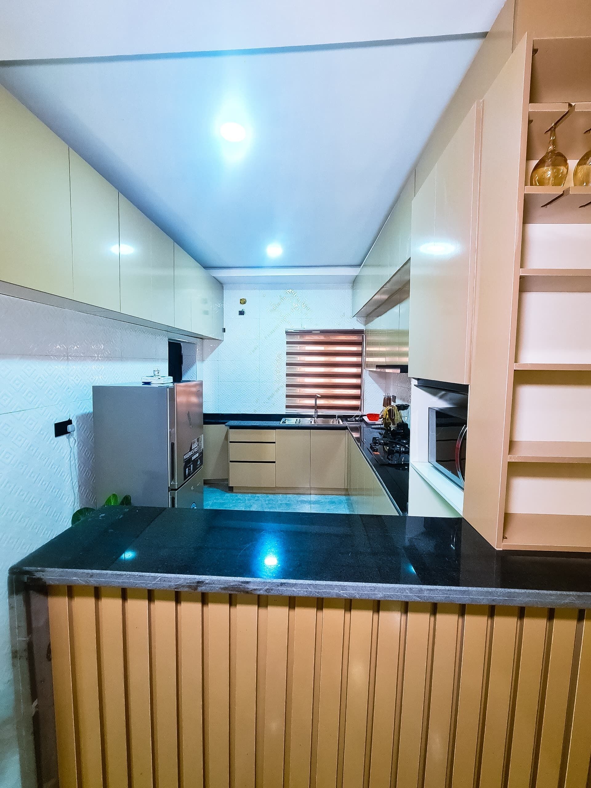 A compact kitchen with a black countertop, white cabinets, and a built-in oven.