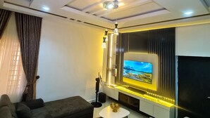 Una sala de estar moderna con un sofá modular, un televisor de pantalla plana e iluminación ambiental.