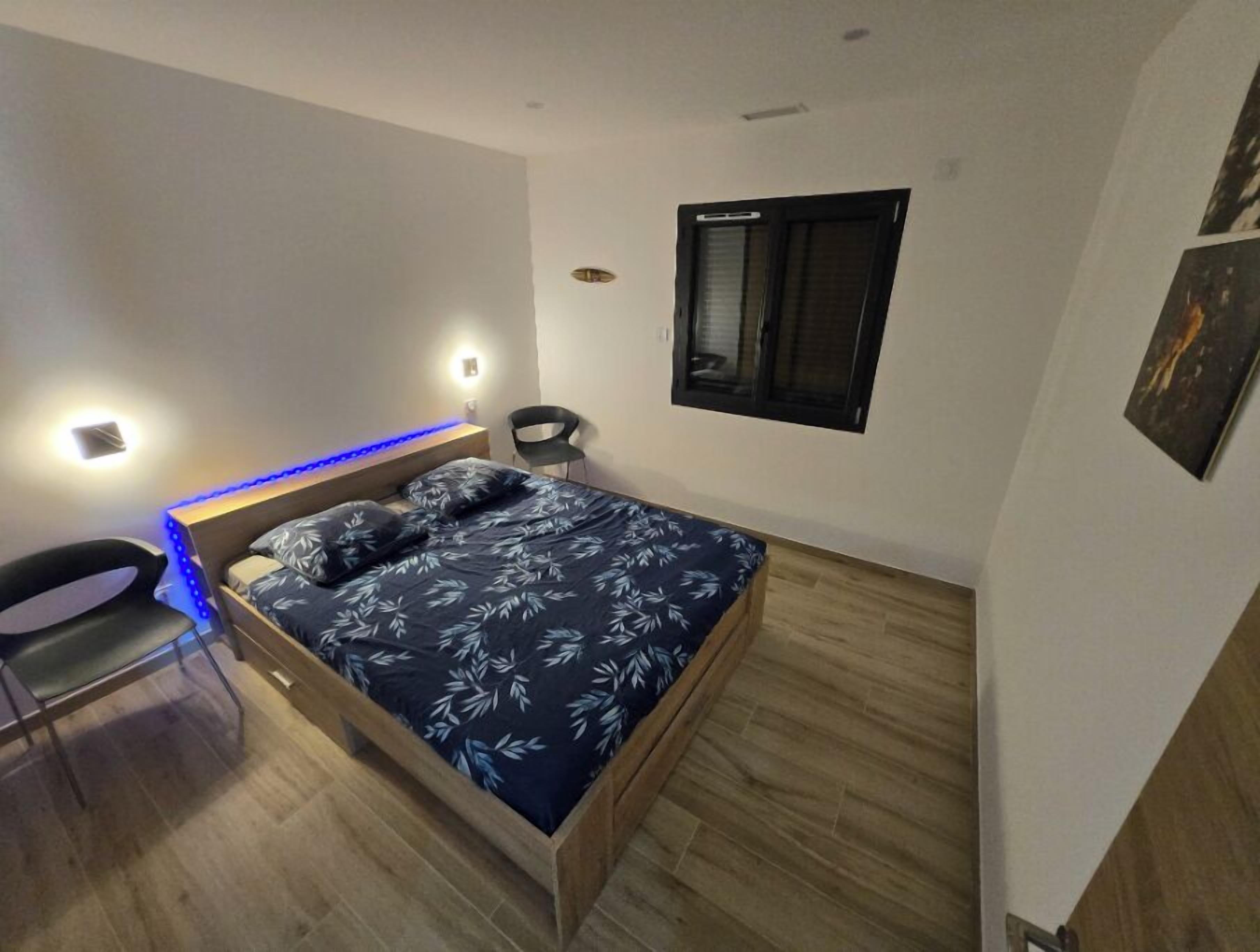 Ein modernes Schlafzimmer mit Bett, Nachttischen, einem Sessel und einem Fenster.