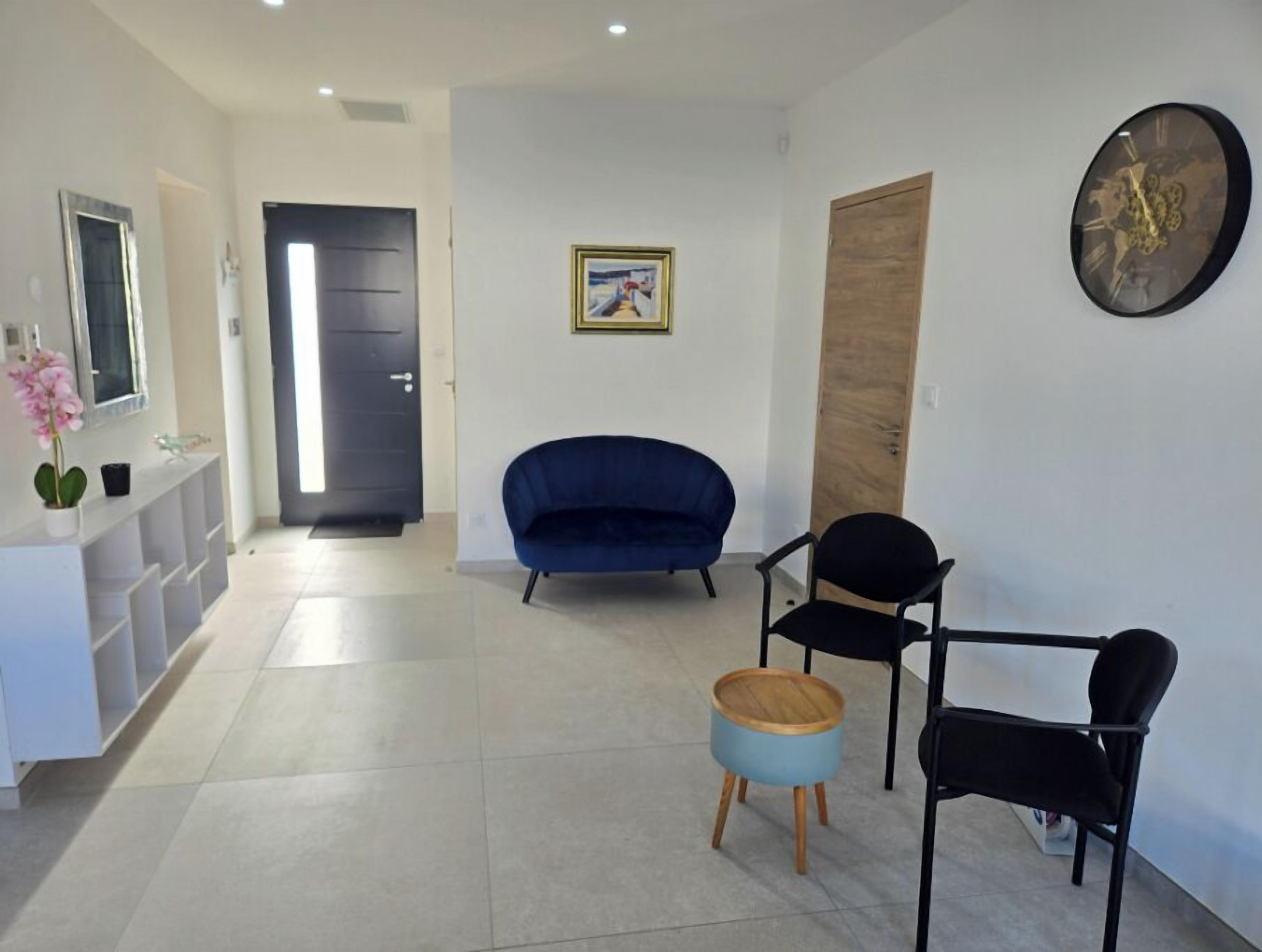 A modern living room with a blue sofa, a black chair, and a small wooden stool.