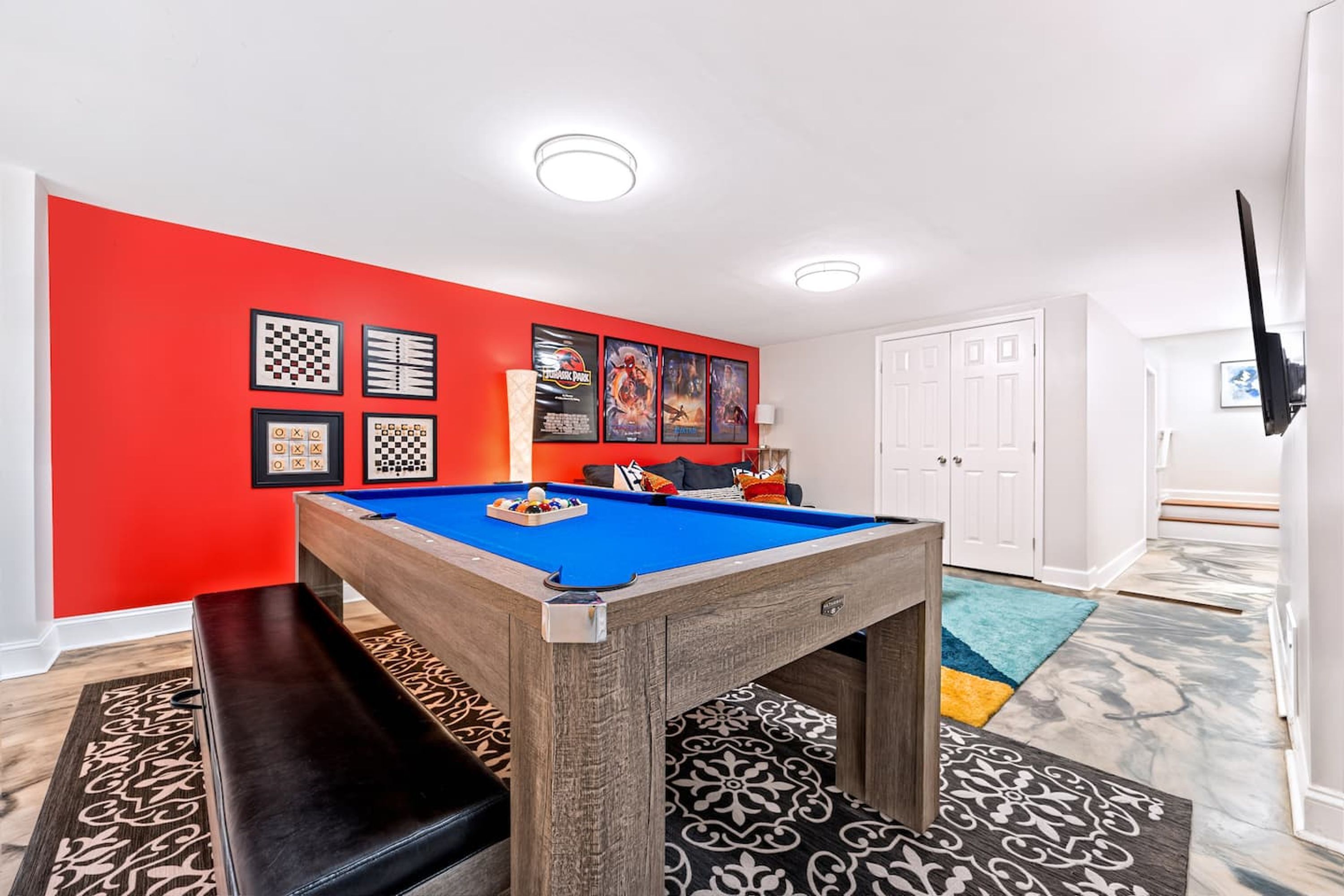 A room with a pool table, a bench, and a red accent wall.