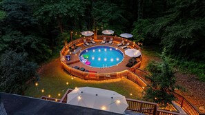 A circular outdoor swimming pool with a wooden deck, surrounded by lounge chairs and umbrellas. - ATL Cascade Oasis - Pool Spa Arcade Pool Tbl (Atlanta)