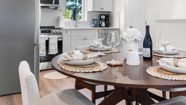 A dining area with a round table set for four, white cabinets, a microwave, and a coffee maker in the background. - Walkable 2BR Close to downtown, hiking, Red Rocks (Denver)