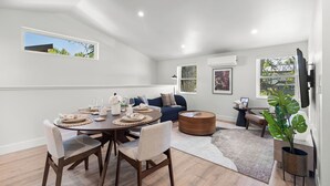 A modern living room with a dining table, chairs, a sofa, a coffee table, and a large plant. - Walkable 2BR Close to downtown, hiking, Red Rocks (Denver)