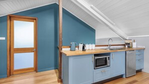 A kitchen with a wooden countertop, a sink, a microwave, and a dishwasher.