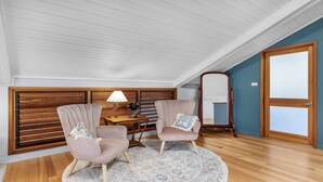 A room with two armchairs, a wooden desk, a lamp, a mirror, and a patterned rug.