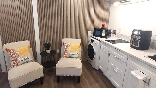 Une cuisine compacte équipée d’un lave-linge, d’une machine à café et d’une petite table agrémentée d’une plante.