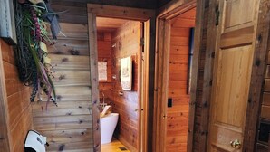 A wooden hallway leading to a bathroom with a white sink and a towel hanging on the wall.