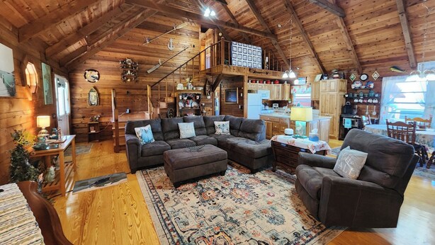 A cozy log cabin interior with a living room, kitchen, and dining area.