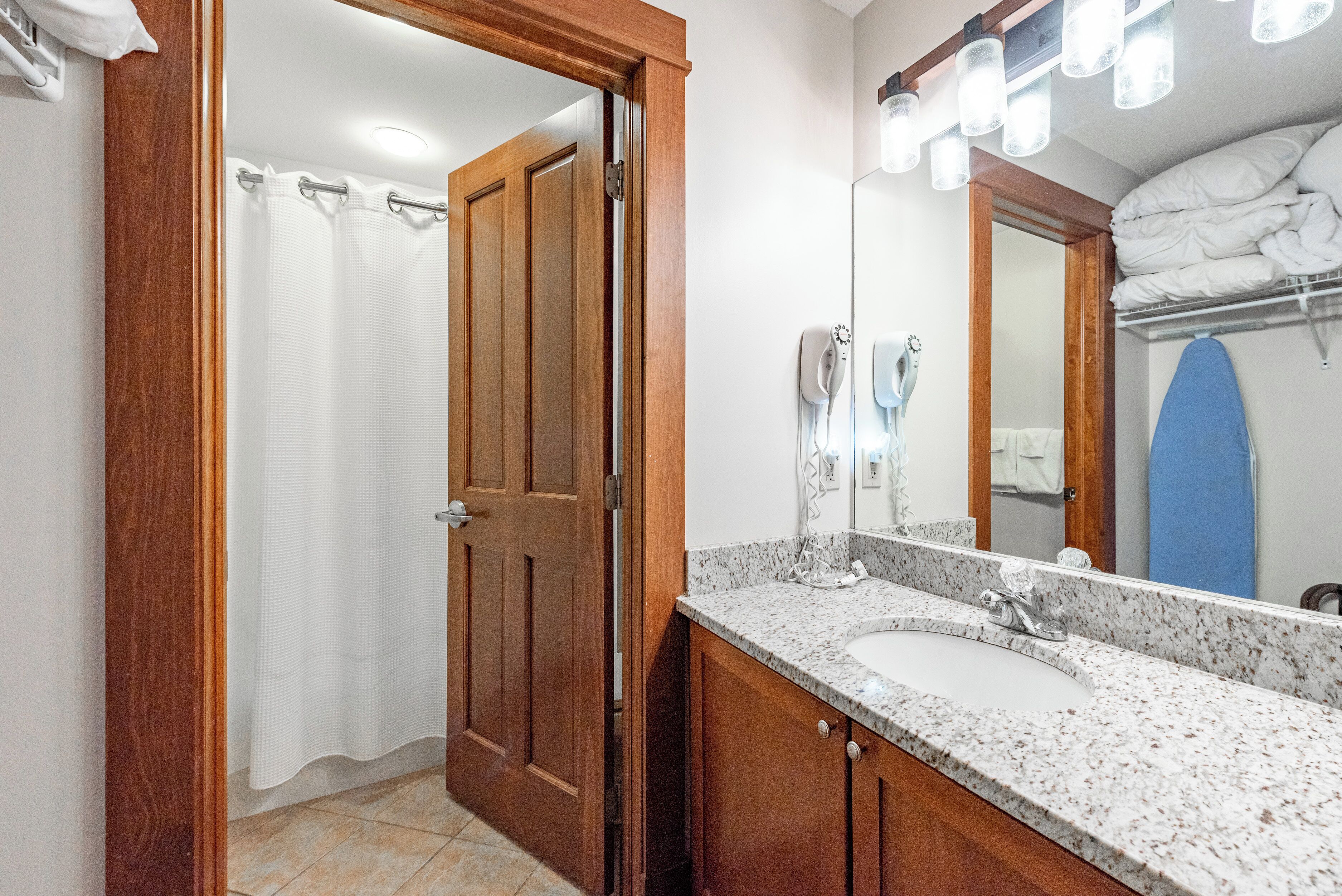 Un baño con puerta de madera, un lavabo blanco, un espejo y un perchero para toallas.